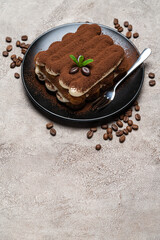 Classic tiramisu dessert on ceramic plate on concrete background
