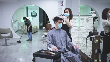 Man client in mask during hair cut by professional hairdresser in mask at beauty salon . High quality FullHD footage