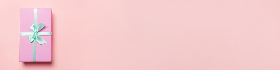 Christmas New Year birthday valentine celebration present romantic concept. Simply minimal design pink gift box isolated on pink pastel colorful background. Flat lay top view copy space, banner