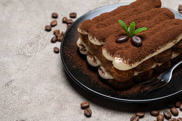 Classic tiramisu dessert on ceramic plate on concrete background