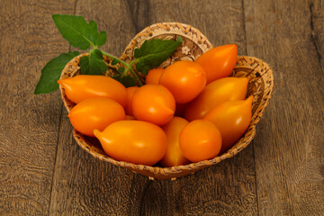 Yellow tomato heap in the wooden bowl