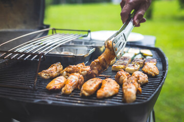 BBQ on weekend. Chicken wings, cheese and vegetables on gas grill. Outdoors.