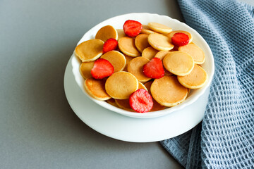 Pancake porridge, mini pancakes with strawberries in a bowl. Dutch mini pancakes are called strawberry and potato pancakes. 
