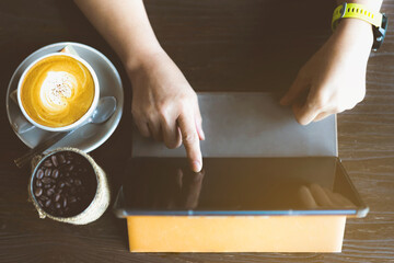 Quarantined woman work from home by using a tablet and stress relief with hot coffee. New normal lifestyle. Selective focus on right index finger.