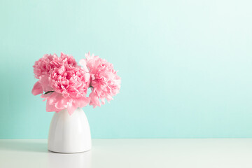 Home decoration with floral decor on table. Beautiful flowers pink peonies in vase on mint...