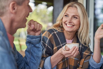 Happy elderly couple talking with cups of hot drinks