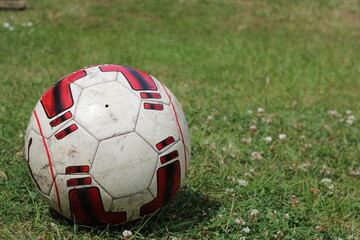 Fototapeta na wymiar dirty red soccer football on grass on a pitch depicting summer ball games