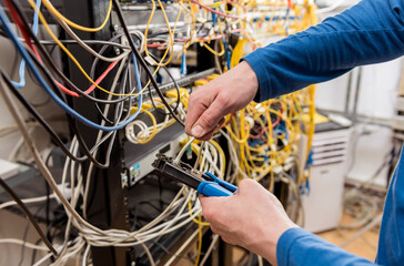 Network engineer working in server room. Connecting network cables to switches