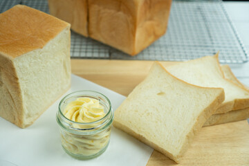 Tosted bread with butter cup and bread loaf on wood plate