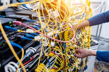 Network engineer working in server room. Connecting network cables to switches