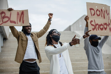 Three protestors holding cardboard signs
