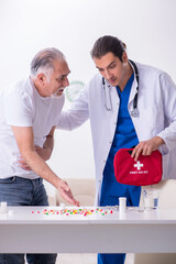 Young male doctor visiting old male patient at home