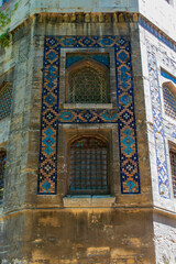 Large historic building covered with tiles. building with large windows and decorated with colorful motifs around it. Historic building with old worn ornaments.