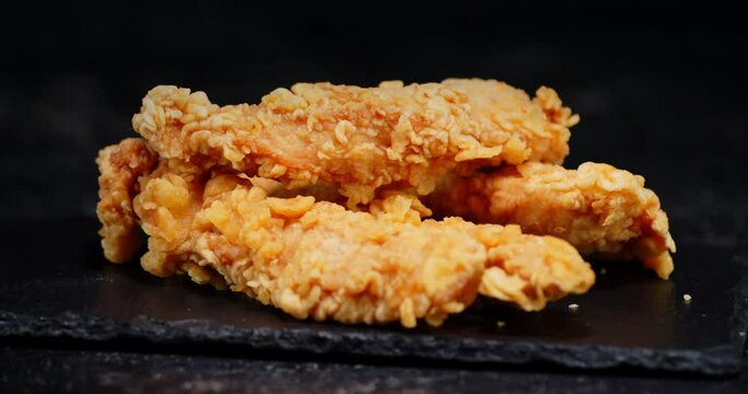 A pile of chicken strips on a stone Board rotates slowly.