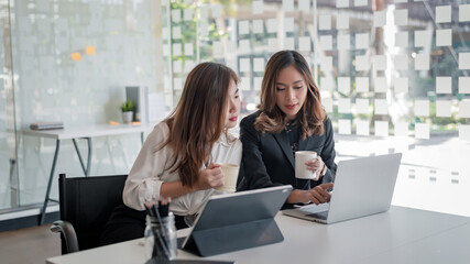 Two business women working together with a laptop computer to explain and discuss on business in the office.