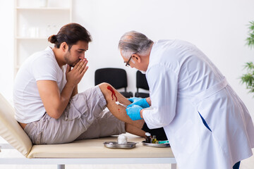 Obraz premium Leg injured man visiting old doctor in first aid concept