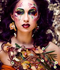 beauty woman with face art and jewelry from flowers orchids close up