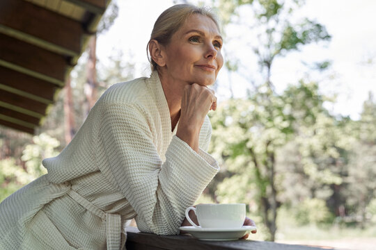 Serene woman with cup of hot drink on terrace outdoors