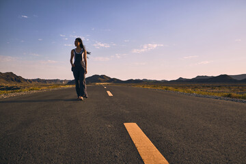 Obraz premium Asian girl walking along the road in between mountains.