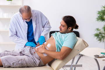 Obraz premium Injured young man visiting experienced male doctor