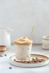 Delicious Dalgona Coffee with sweet foam and ice in a glass with a straw. Gray background. cold...