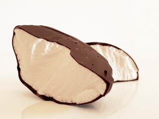 Two halves of broken marshmallow in chocolate on a white background in the studio. Isolated.