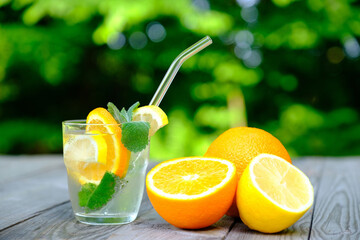Homemade lemonade with orange mint and lemon slice ingredients on wooden table. Refreshing Summer cocktail concept.