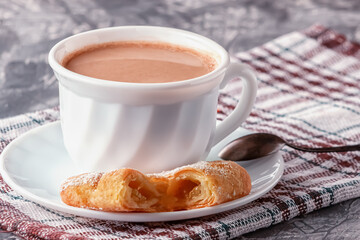 Coffee with cream and freshly baked puffs on a gray background