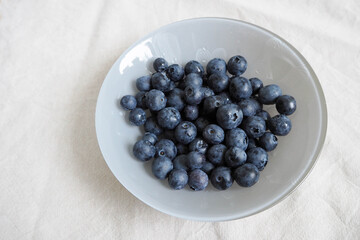 grey glass round plate with blue blueberries on a grey table