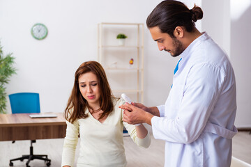 Fototapeta premium Young hand injured woman visiting male doctor traumatologist