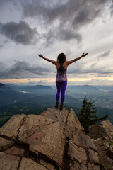 Adventurous Girl on top of a Rocky Mountain overlooking the beautiful Canadian Nature Landscape during a dramatic Sunset. Taken in Chilliwack, East of Vancouver, British Columbia, Canada.