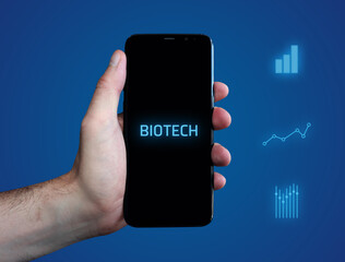 Biotech. Hand hält Telefon (Handy). Wort auf Display. Diagramme auf Hintergrund blau. Business