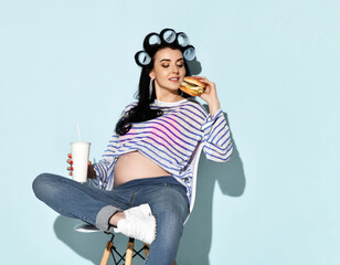 Portrait of pregnant brunette woman in blue jeans, stripy t-shirt sits on stylish chair going to...