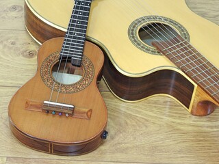 Fototapeta premium Close-up of an acoustic guitar and a Brazilian string musical instrument: cavaquinho, on a wooden surface. They are widely used to accompany samba and choro, two popular Brazilian rhythms. Top view.