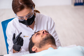 Fototapeta premium Young man visiting female beautician in hair transplantation con