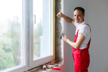 worker in uniform installs a plastic sandwich panel on the slopes of the window