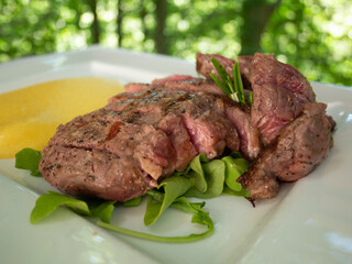A plate of rare sliced beef with polenta. Undercooked meat. Tagliata di Manzo