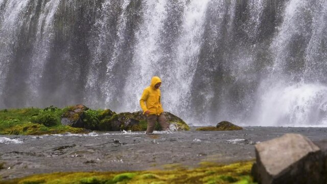 Man walking through water, in front of the Dynjandi waterfall, in Westfjords, Iceland, Slow motion shot
