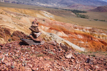 Stone cairn on the red earth in the mountains. Mars valley in the Altai mountains