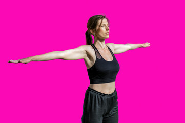 Young woman doing gymnastics on a pink background.