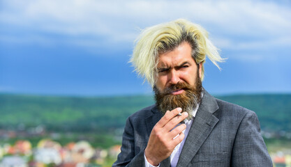 mature man smoking cigarette. brutal male with dyed hair in blonde. serious caucasian hipster with...