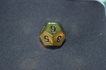 Gold metallic d12 twelve sided dice on foam surface