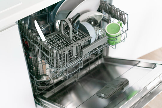 Opened And Loaded On Half Dishwasher Machine With Green Cup And Steel Knife. Gray Painted Shelves Inside. Plate Cleaner. Helpful. Kitchen. Built In Device In Furniture