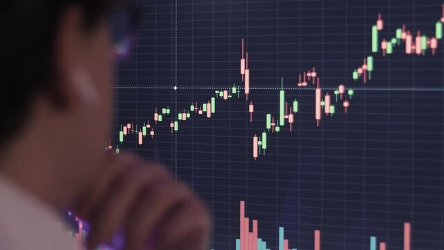 Businessman analyzing a graphic of a stock exchange chart. Back of the head of a young male businessman looking at a stock diagram on the big screen of the computer