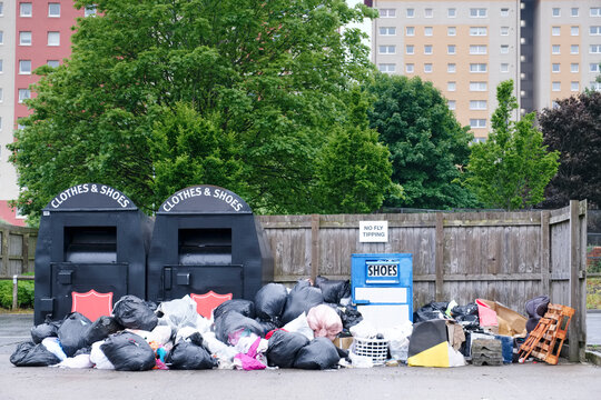 Clothes and shoes charity recycle container and black bin bags in a group dump in. council estate