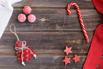New year flat lay: Christmas linen tree with hearts, candy cane, tiny snow sugar apples, white woolen plaid and red tablecloth with stars on a rustic wooden background