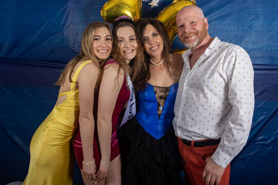 Family Of Four With Mom, Dad And Two Teenage Daughters Pose Together For A Group Portrait During A Birthday Party