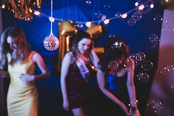 Group of three girls dancing and having fun at a birthday party with a disco ball