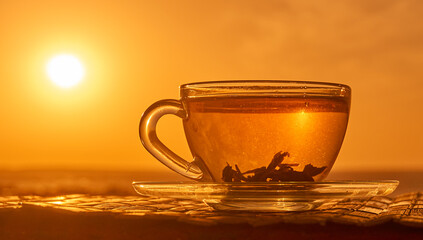 Tea cup with tea leaves in sunset. 