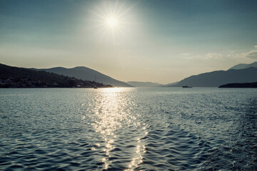 The bright sun on the sea with a view of the mountains. Adriatic Sea in Montenegro. Tourism and travel. Space for text.